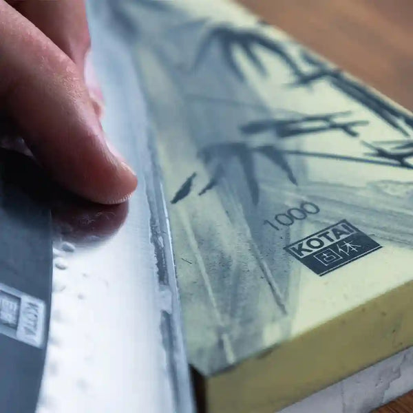 The model is sharpening the knife on the whetsone or waterstone.