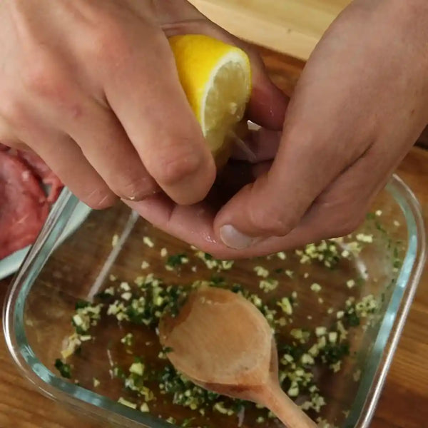 The model is pouring lemon juice on the herbs and parmesan mixture. 