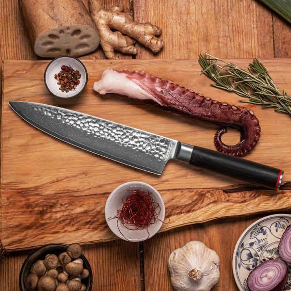 KOTAI's Gyuto also known as Chef's knife, displayed on a wood cutting board next to different ingredients; mushrooms, garlic, onions, octopus…