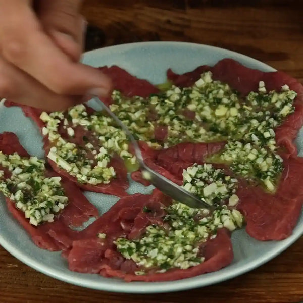 Spreading the delicious mixture on the beef slices.