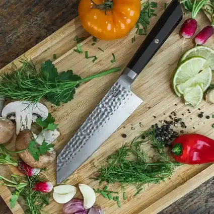 Le Santoku Bunka de KOTAI en acier japonais 440C résistant à la rouille est posé sur une planche à découper entouré de légumes colorés.