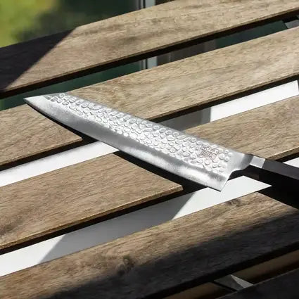 Le couteau de chef japonais Kiritsuke de la collection Bunka sous le soleil qui reflète son joli martelage.