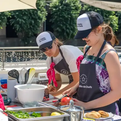 Des compétitrices de la Tablée des Chefs cuisinent en souriant.