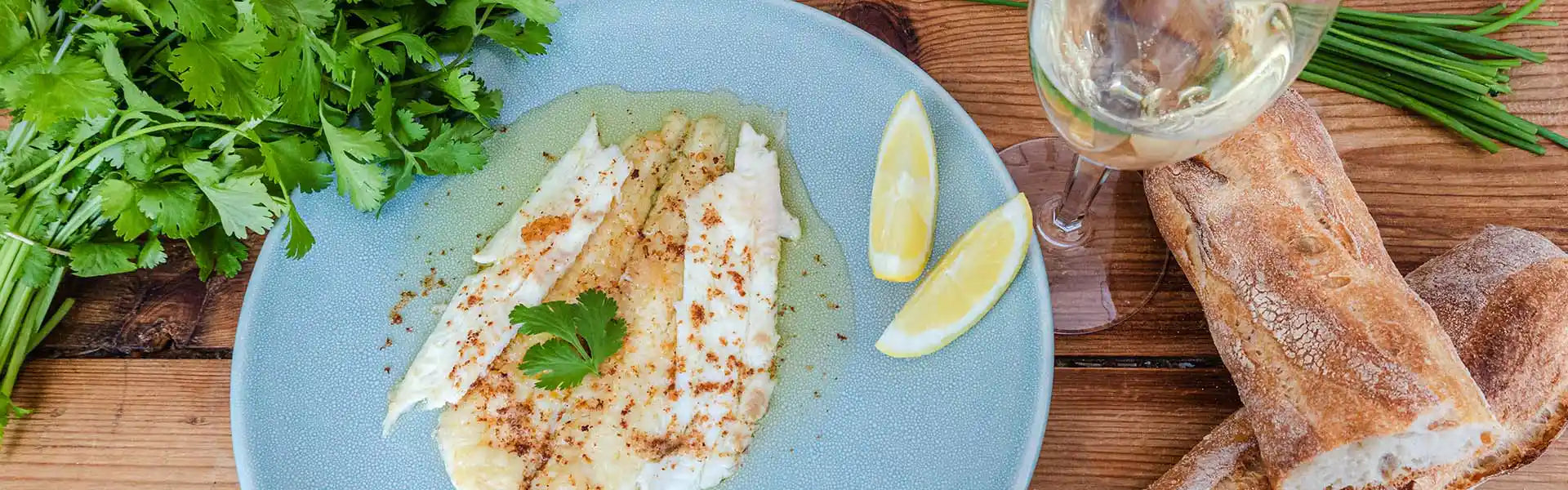 French classic dish sole meunière displayed on a ceramic place served with a glass of white wine. 