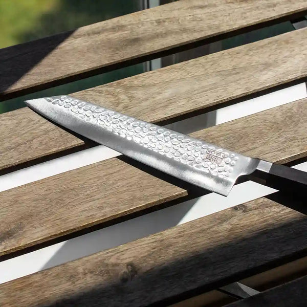 KOTAI's Kiritsuke chef knife kept on a wooden table under sunlight. 