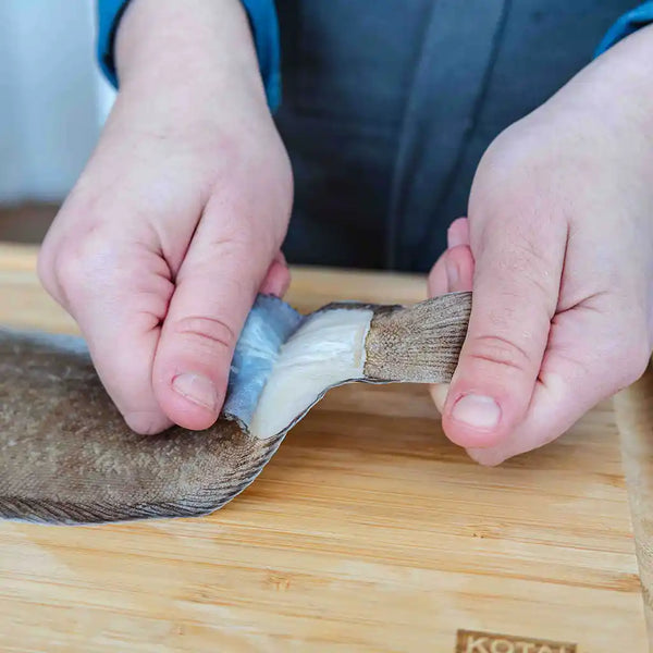 The model is pulling off the skin of the sole fish. 