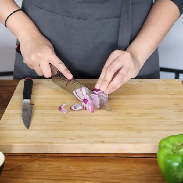 Model is slicing an onion on KOTAI's bamboo cutting board. 