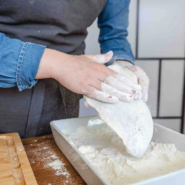 The model is spreading the flour on a plate and dredging the fillets in it.