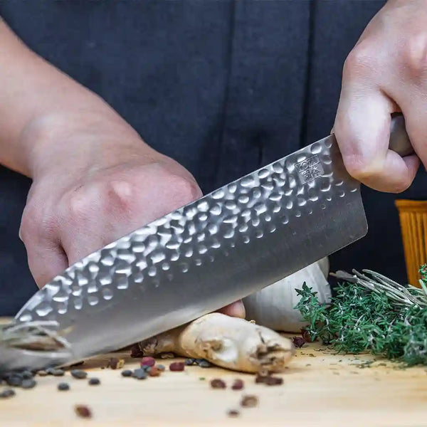 Model is cutting a piece of ginger with KOTAI's Santoku kitchen knife.