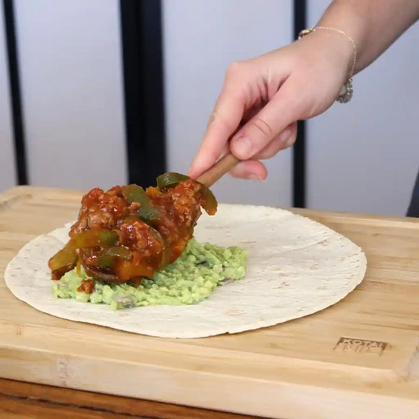 The model is spreading the minced beef mixture on the tortillas.