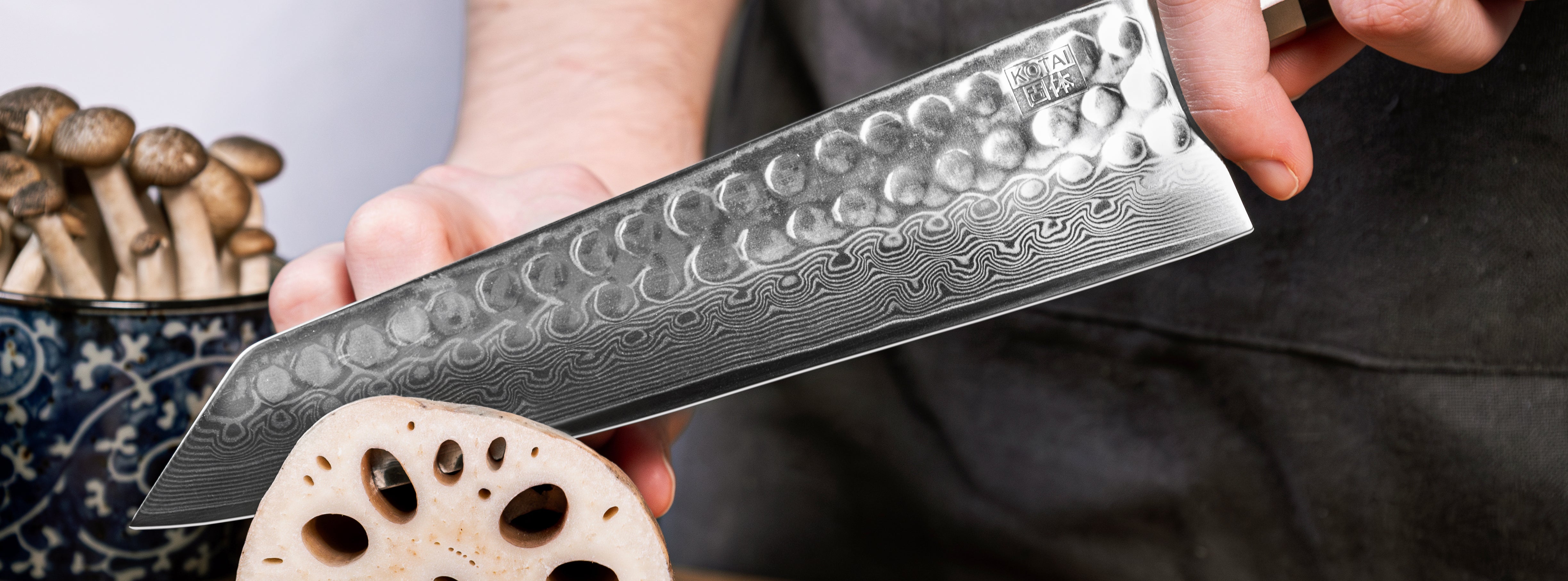 model hands are holding the kiristuke bunka collection in damascus steel to cut an ingredient
