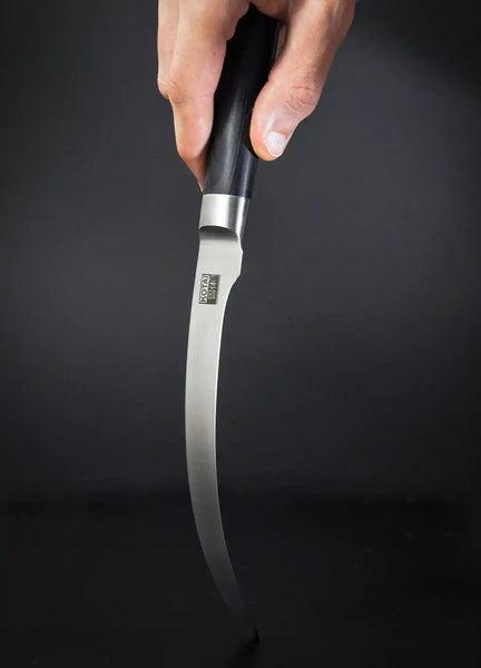 A hand is holding the KOTAI's Fillet Knife while testing its flexibility by bending the blade, on a black background.
