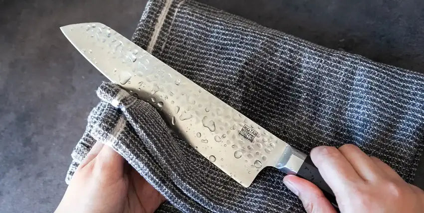 The model is holding a hand-washed KOTAI knife with a piece of cloth to wipe the water, contributing to good maintenance of the kitchen knife.