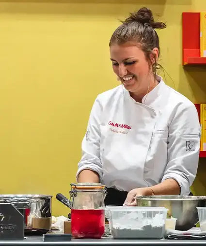 Chef Tiphane Mollard dans son uniforme de chef blanc en train de cuisiner.