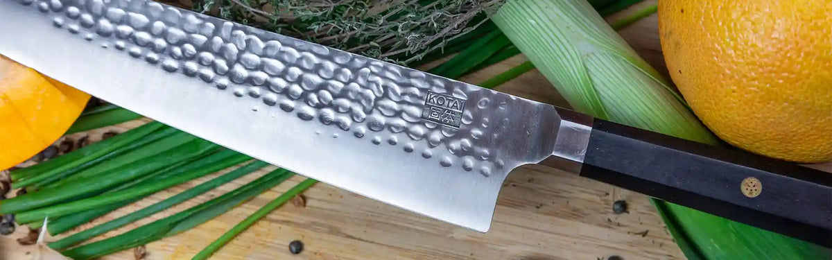 KOTAI knife displayed on a cutting board along with colorful vegetables. 