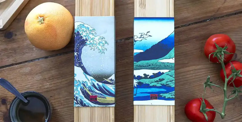 Les élégantes boites en bambou des couteaux japonais Gyuto et Santoku côte à côte sur une table en bois.