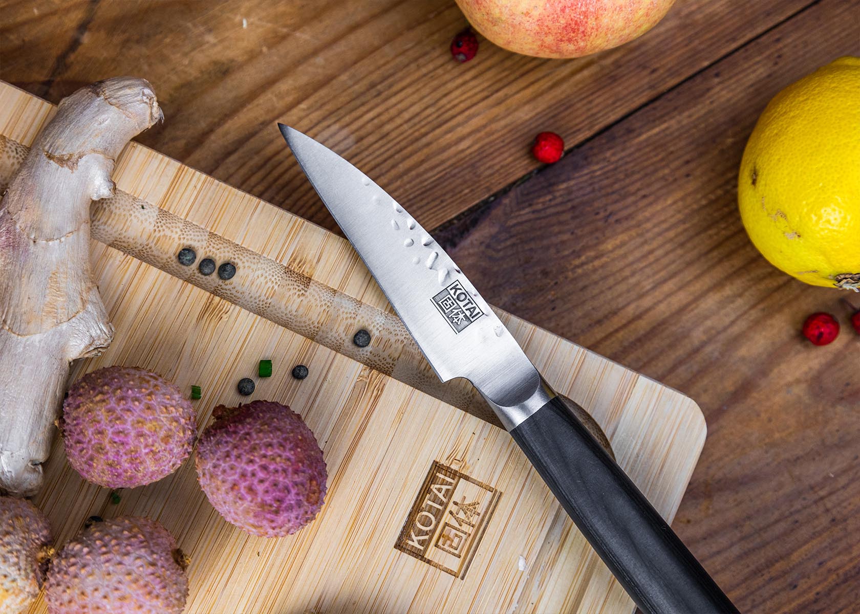 KOTAI Paring knife 90 mm blade and pakkawood handle on KOTAI bamboo cutting board with fruits.