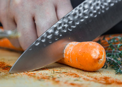 Cutting a carrot with KOTAI Gyuto 200 mm blade and pakkawood handle on cutting board.