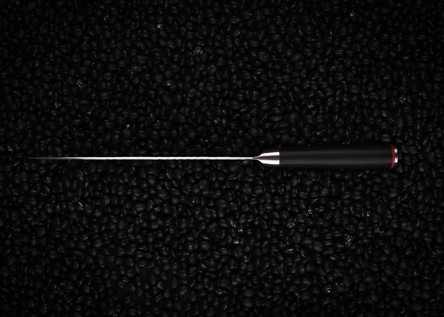 KOTAI Gyuto seen from the top on black beans background.
